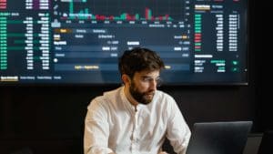 Man in front of large dashboard looking at computer.