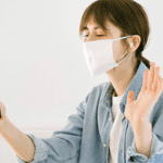 Woman waving at phone while wearing a mask