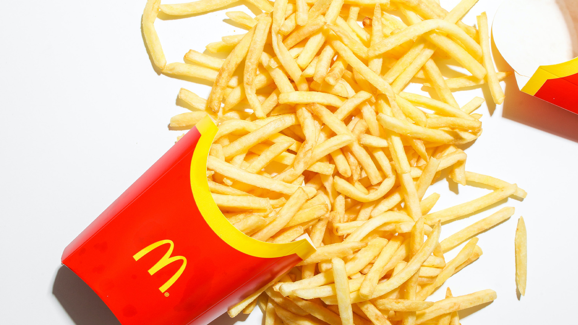 A pile of spilled french fries coming out of a McDonalds container