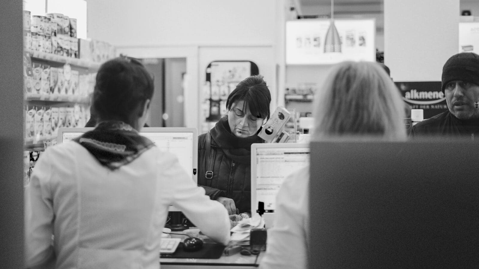 People standing at a counter at a pharmacy