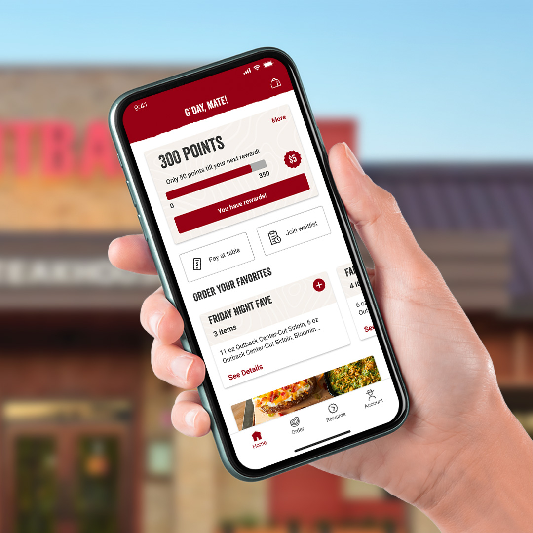Home screen in the new Outback Steakhouse application on phone in front of Outback restaurant.