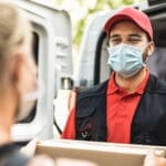 delivery driver with face mask on handing a package to a customer