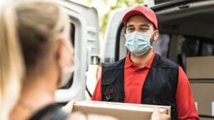 delivery driver with face mask on handing a package to a customer