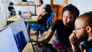 a man and woman working on a computer in an office setting